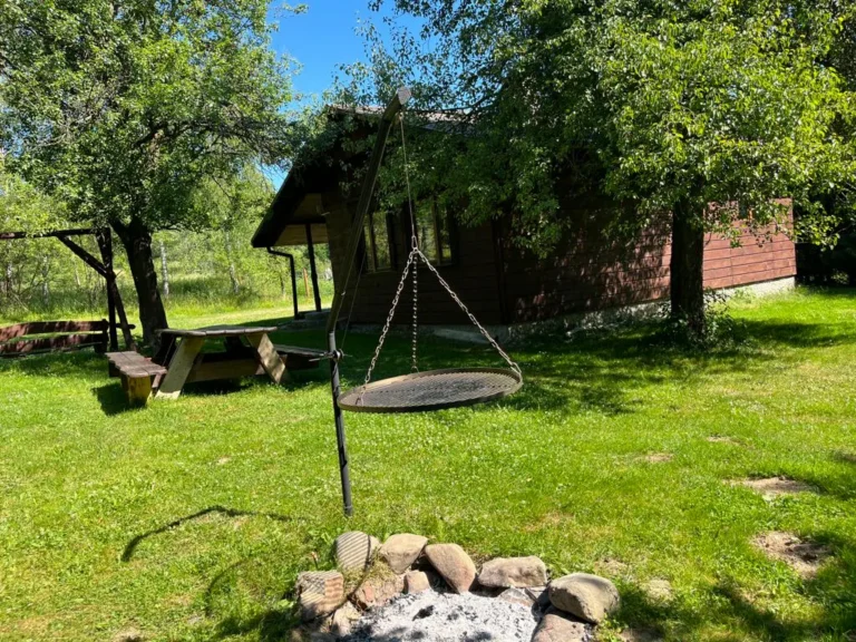 Palenisko z rusztem zawieszonym na trójnogu przy domku — domek parterowy WOLF, domki W Dolinie Sanu w Zatwarnicy (Bieszczady)